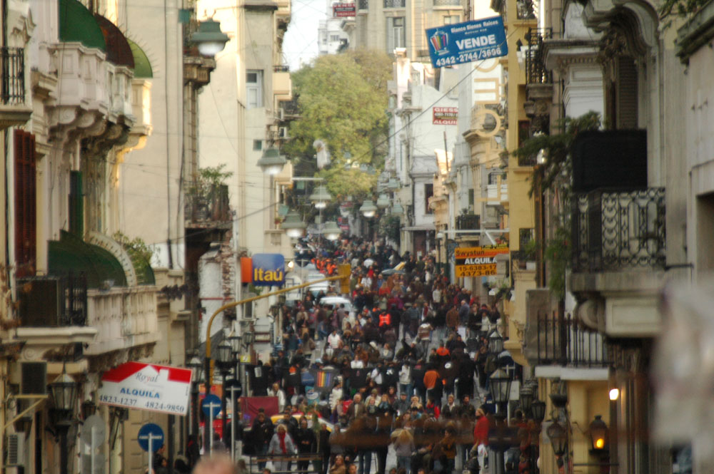Figura 4. Defensa, un domingo cualquiera. Por encima de la multitud se destacan los carteles de departamentos en venta o alquiler, acentuando el proceso de recambio poblacional (fotografía de Constanza Gnecco).